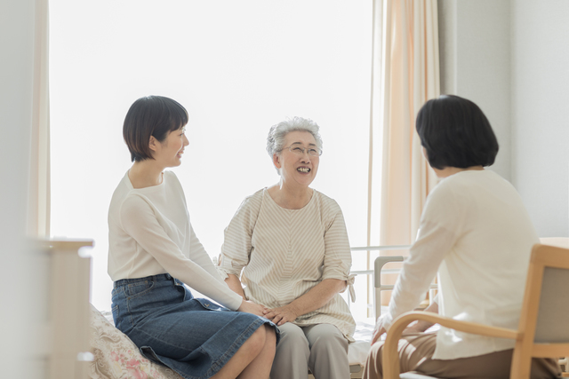 介護ベッドに座り談話する女性の写真